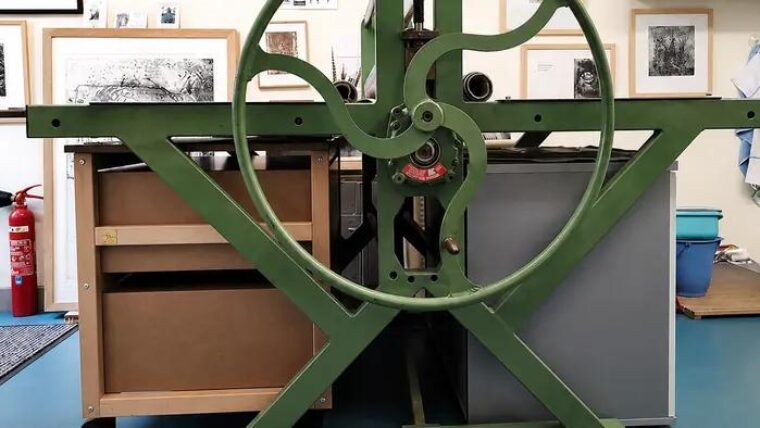 Meuble à plans Auboi vu depuis l’autre côté de la presse taille-douce, gravures encadrées au mur de l’atelier