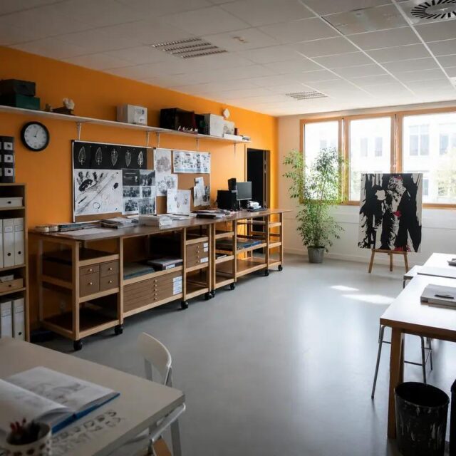 Salle d’arts appliqués du lycée Suger : rangée de meubles atelier Auboi le long d’un mur orange